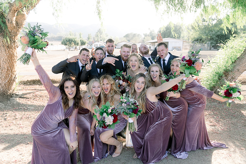  a lavender and black wedding in a garden – with the bride in a long sleeve lace gown and the groom in a black tuxedo – bridal party 