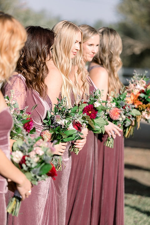  a lavender and black wedding in a garden – with the bride in a long sleeve lace gown and the groom in a black tuxedo – bridesmaids at the ceremony 