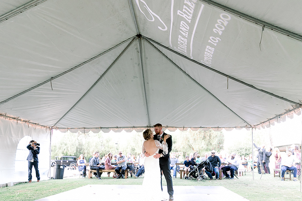  a lavender and black wedding in a garden – with the bride in a long sleeve lace gown and the groom in a black tuxedo – first dance