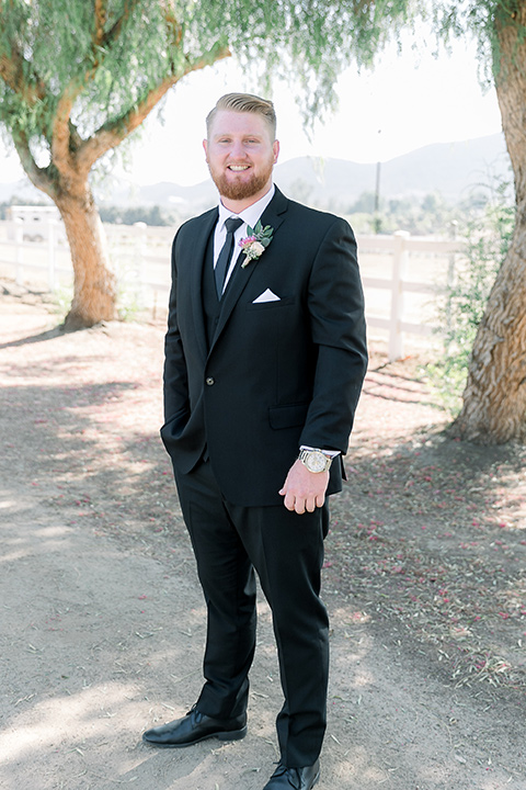  a lavender and black wedding in a garden – with the bride in a long sleeve lace gown and the groom in a black tuxedo – groom 