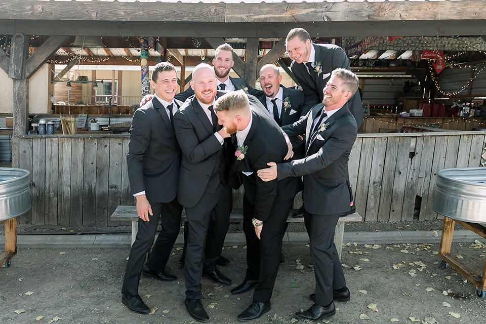  a lavender and black wedding in a garden – with the bride in a long sleeve lace gown and the groom in a black tuxedo – groomsmen