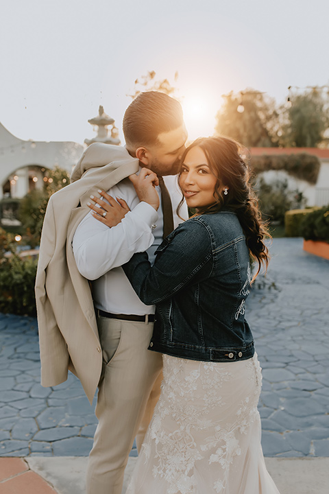  romantic neutral wedding with Spanish flare – couple kissing and the bride in a jean jacket