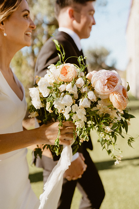  blush and beige wedding with a chic modern twist – the bride in a cap sleeved fitted gown and the groom in a black suit – walking down the altar