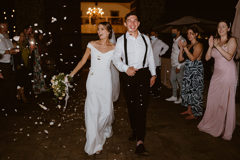  blush and beige wedding with a chic modern twist – the bride in a cap sleeved fitted gown and the groom in a black suit – leaving the wedding