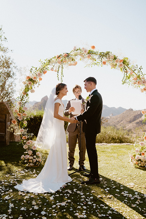  blush and beige wedding with a chic modern twist – the bride in a cap sleeved fitted gown and the groom in a black suit – ceremony