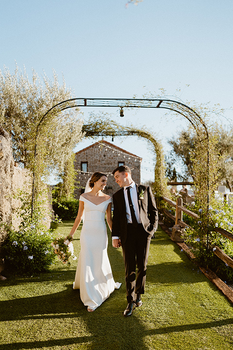  blush and beige wedding with a chic modern twist – the bride in a cap sleeved fitted gown and the groom in a black suit – couple walking