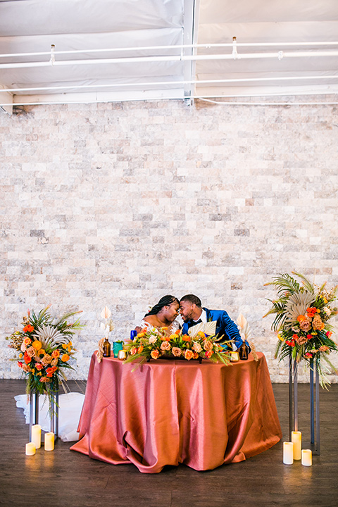  jewel toned wedding with the bride in a ballgown and the groom in a blue velvet tuxedo – sitting at sweetheart table