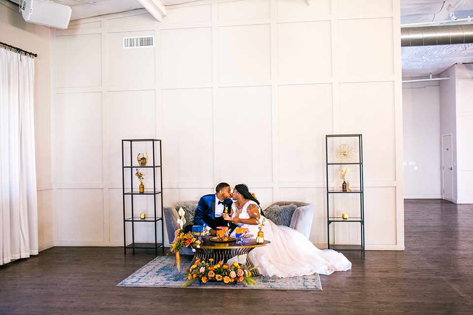  jewel toned wedding with the bride in a ballgown and the groom in a blue velvet tuxedo – sitting on the couch