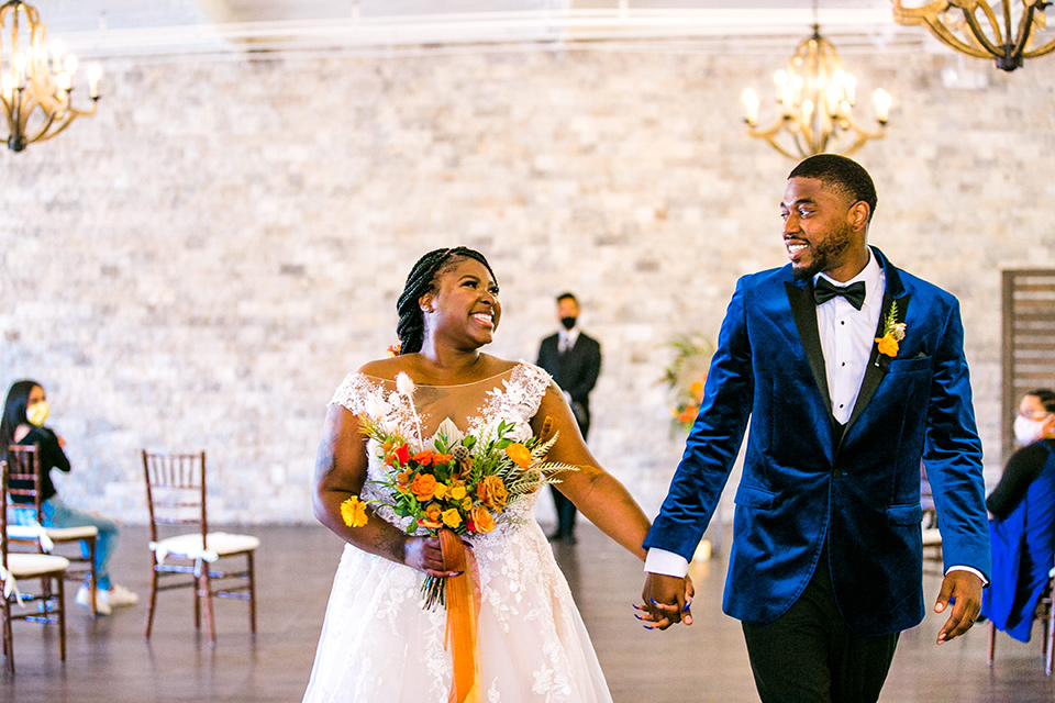  jewel toned wedding with the bride in a ballgown and the groom in a blue velvet tuxedo – walking down the aisle