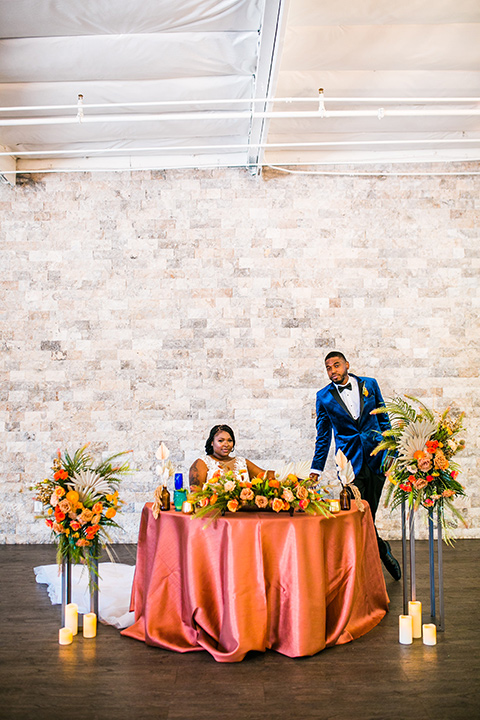  jewel toned wedding with the bride in a ballgown and the groom in a blue velvet tuxedo – sitting at sweetheart table 