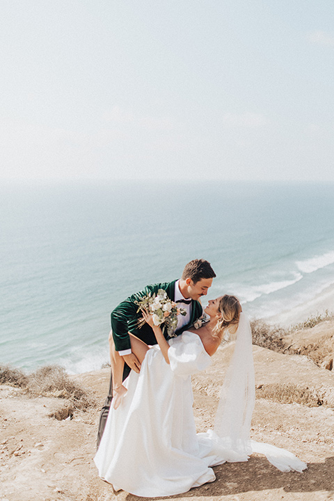  elopement on the cliffs with the bride in a ball gown with poof sleeves and the groom in a green velvet tuxedo 