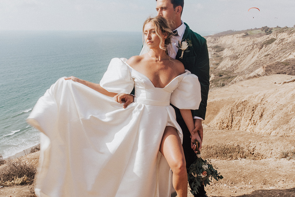  elopement on the cliffs with the bride in a ball gown with poof sleeves and the groom in a green velvet tuxedo 