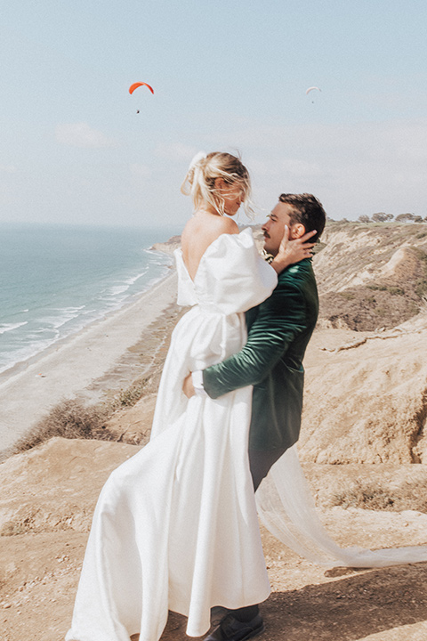  elopement on the cliffs with the bride in a ball gown with poof sleeves and the groom in a green velvet tuxedo 