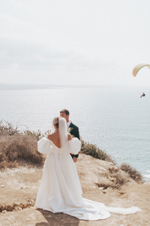  elopement on the cliffs with the bride in a ball gown with poof sleeves and the groom in a green velvet tuxedo 