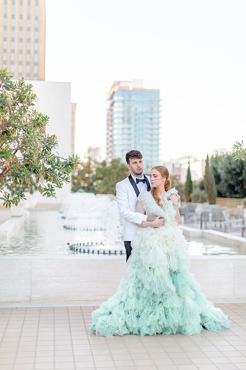  fun wedding at the Westgate hotel and the bride in a blue tulle gown and the groom in a white and black tuxedo - couple outside by fountain 