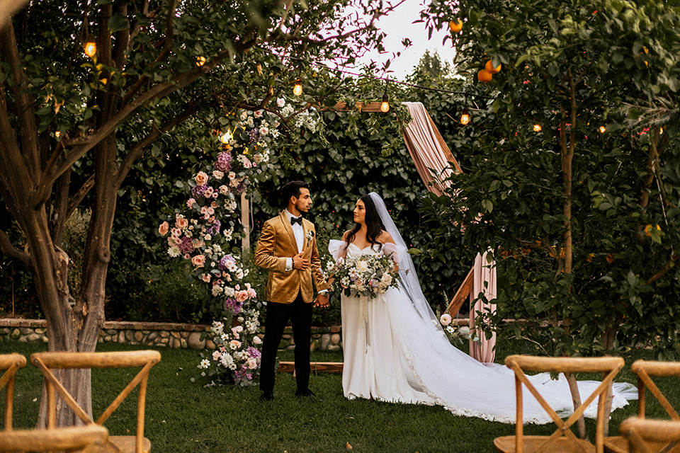  whimsical fairytale wedding with the groom in a gold velvet tuxedo – couple at ceremony