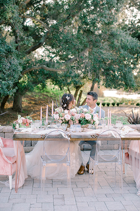  whimsical romance wedding with the bride in a ballgown and the groom in a light grey suit – couple at reception table