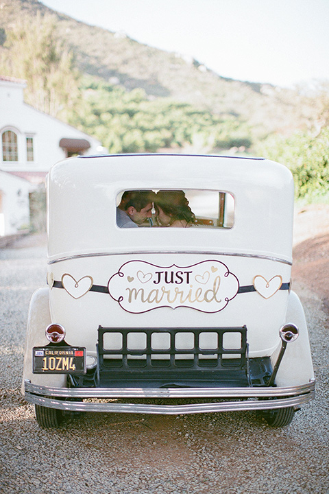  whimsical romance wedding with the bride in a ballgown and the groom in a light grey suit – couple by the car
