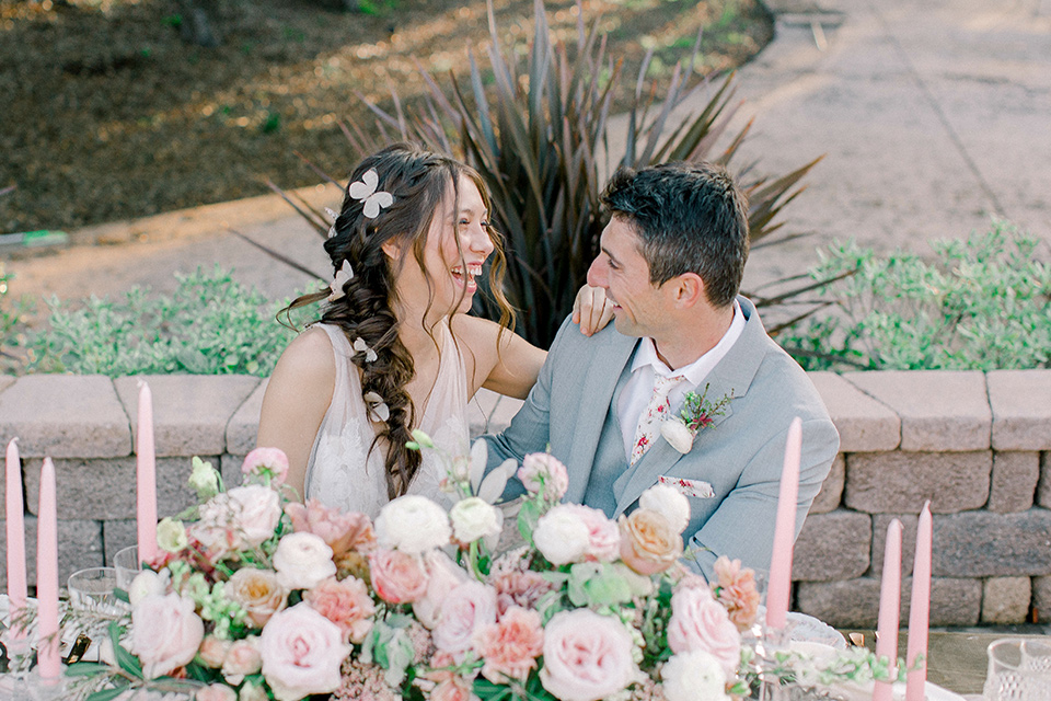  whimsical romance wedding with the bride in a ballgown and the groom in a light grey suit – couple at table
