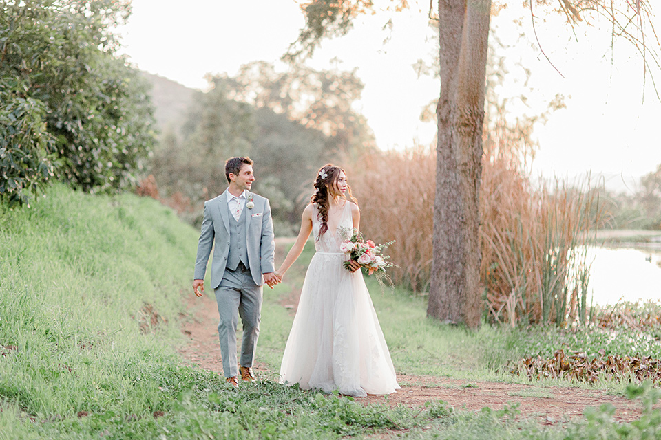  whimsical romance wedding with the bride in a ballgown and the groom in a light grey suit – couple walking