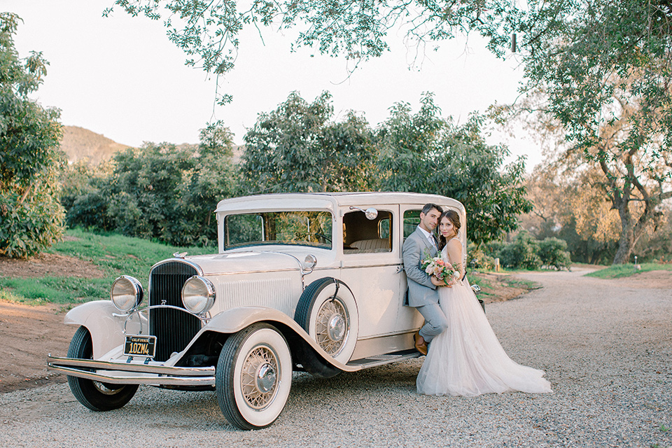  whimsical romance wedding with the bride in a ballgown and the groom in a light grey suit – couple by the car