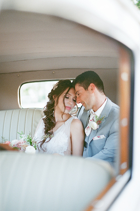 whimsical romance wedding with the bride in a ballgown and the groom in a light grey suit – couple by the car 
