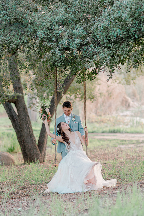  whimsical romance wedding with the bride in a ballgown and the groom in a light grey suit – on the swing 