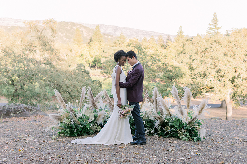  wine country wedding with the bride in a jumpsuit and the groom in a burgundy tux- ceremony 