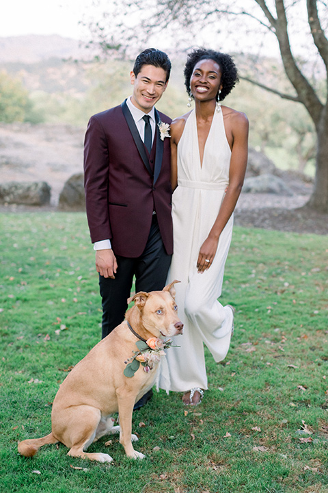  wine country wedding with the bride in a jumpsuit and the groom in a burgundy tux- couple with dog
