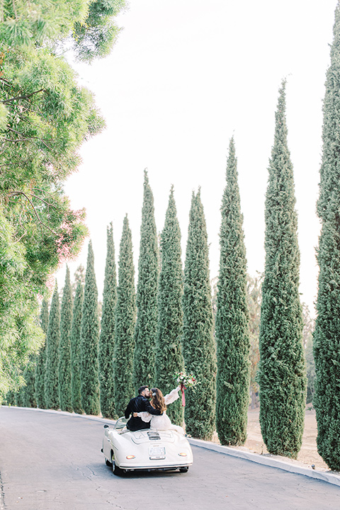  black and white modern wedding at the caramel mountain estate with the bride in a lace gown and the groom in a black velvet tuxedo – vintage car 