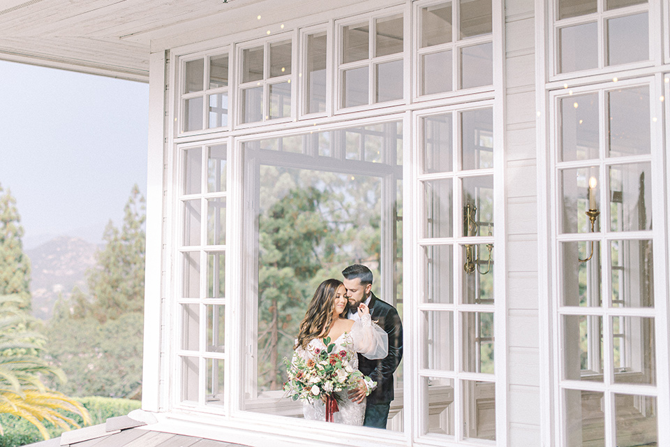  black and white modern wedding at the caramel mountain estate with the bride in a lace gown and the groom in a black velvet tuxedo – couple on the balcony 