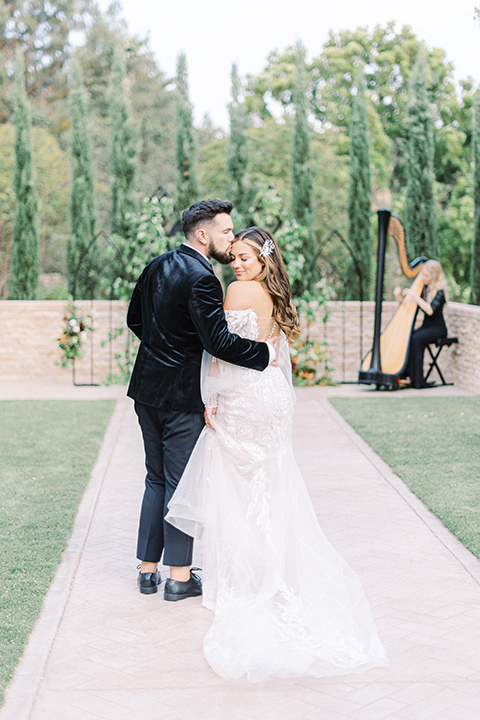  black and white modern wedding at the caramel mountain estate with the bride in a lace gown and the groom in a black velvet tuxedo –  couple walking 