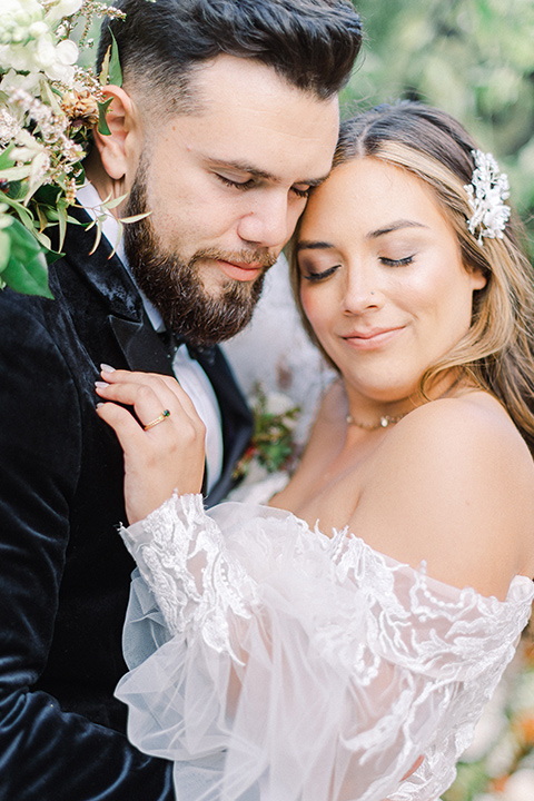  black and white modern wedding at the caramel mountain estate with the bride in a lace gown and the groom in a black velvet tuxedo – couple embracing 