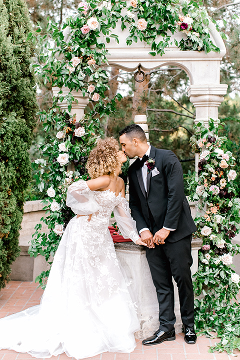  black and white classic wedding with the bride in a modern ballgown with billow sleeves and the groom in a black tuxedo – couple at ceremony 