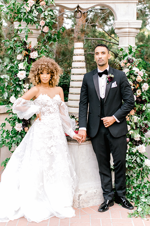  black and white classic wedding with the bride in a modern ballgown with billow sleeves and the groom in a black tuxedo – couple at ceremony 