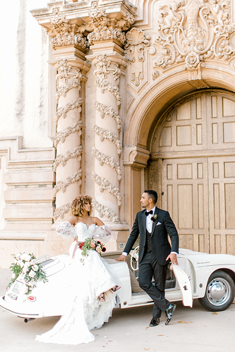  black and white classic wedding with the bride in a modern ballgown with billow sleeves and the groom in a black tuxedo – couple by the car 