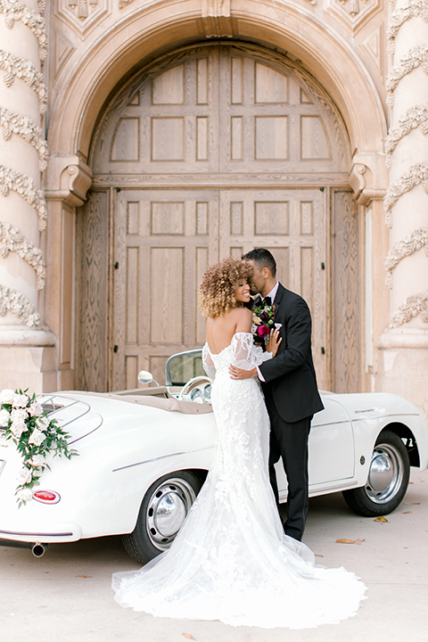  black and white classic wedding with the bride in a modern ballgown with billow sleeves and the groom in a black tuxedo – couple by the car 
