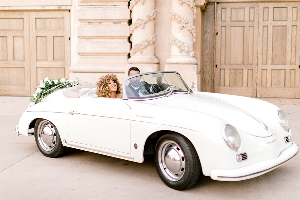  black and white classic wedding with the bride in a modern ballgown with billow sleeves and the groom in a black tuxedo – couple in the car