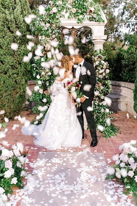  black and white classic wedding with the bride in a modern ballgown with billow sleeves and the groom in a black tuxedo – first kiss 