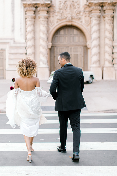  black and white classic wedding with the bride in a modern ballgown with billow sleeves and the groom in a black tuxedo – couple walking across the street 