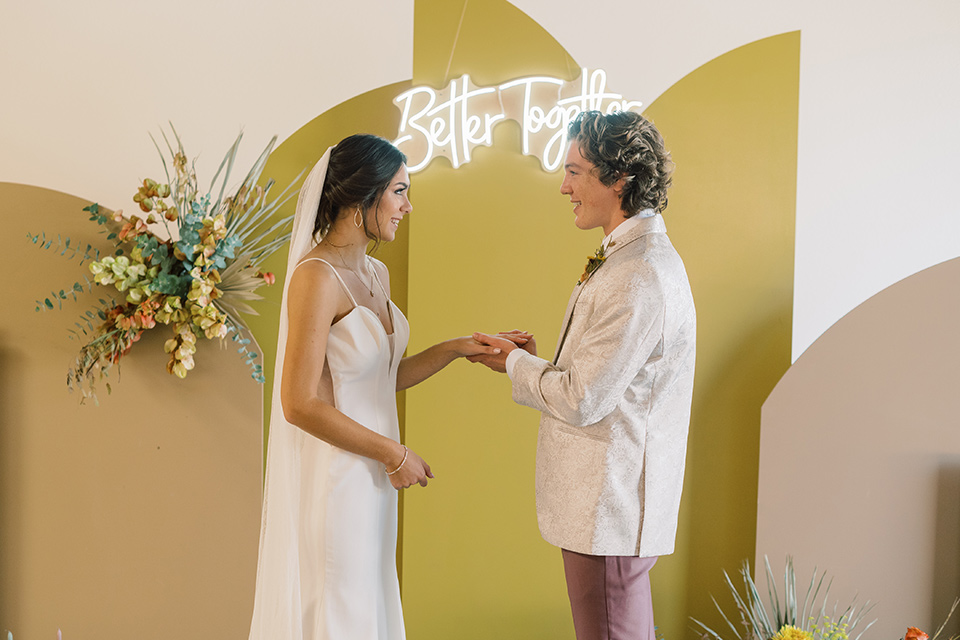  colorful modern wedding with the bride in a fitted gown and the groom in an ivory coat and pink pants – vows