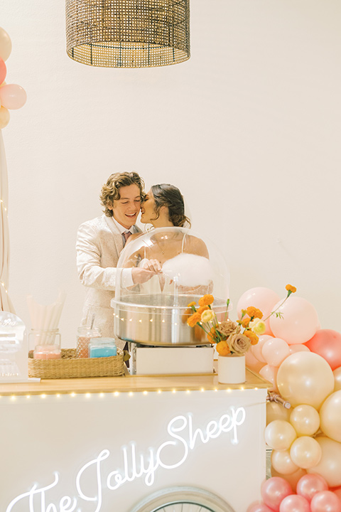  colorful modern wedding with the bride in a fitted gown and the groom in an ivory coat and pink pants – couple with cotton candy 