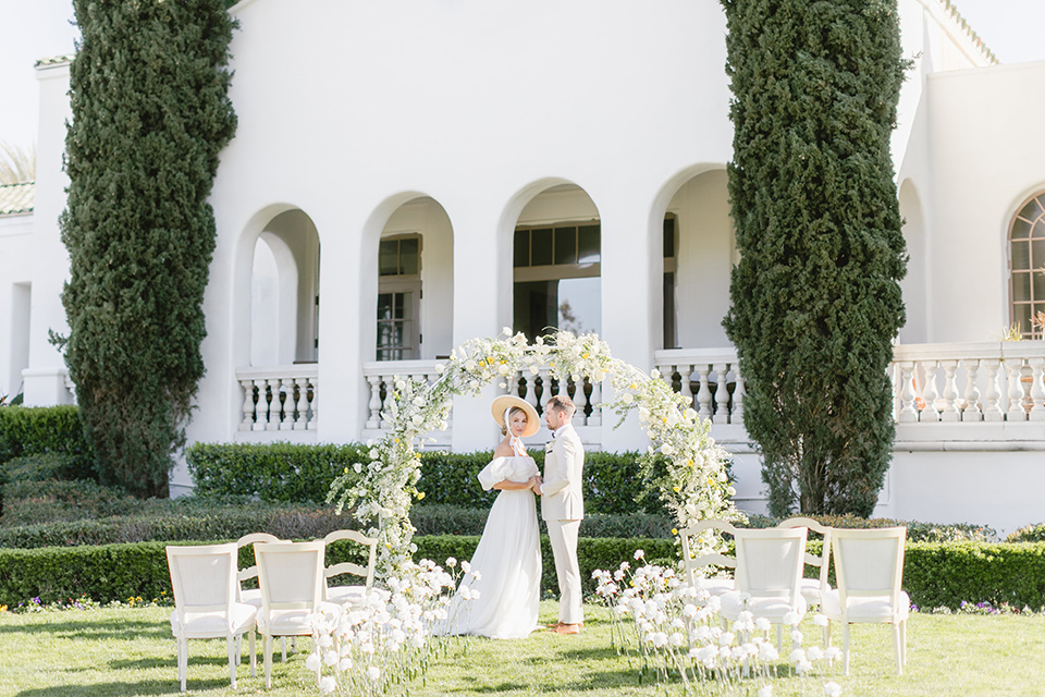  English garden romantic wedding with the bride in an off-the-shoulder gown and the groom in a tan suit – couple at ceremony 