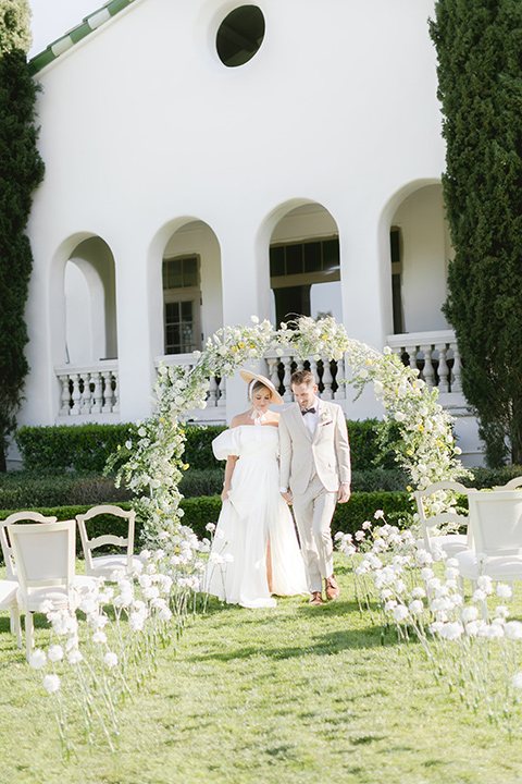  English garden romantic wedding with the bride in an off-the-shoulder gown and the groom in a tan suit – couple at ceremony 