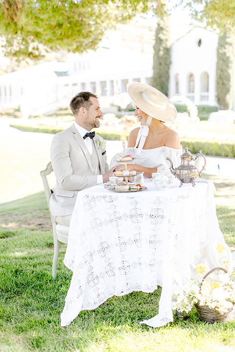  English garden romantic wedding with the bride in an off-the-shoulder gown and the groom in a tan suit – couple at the table 