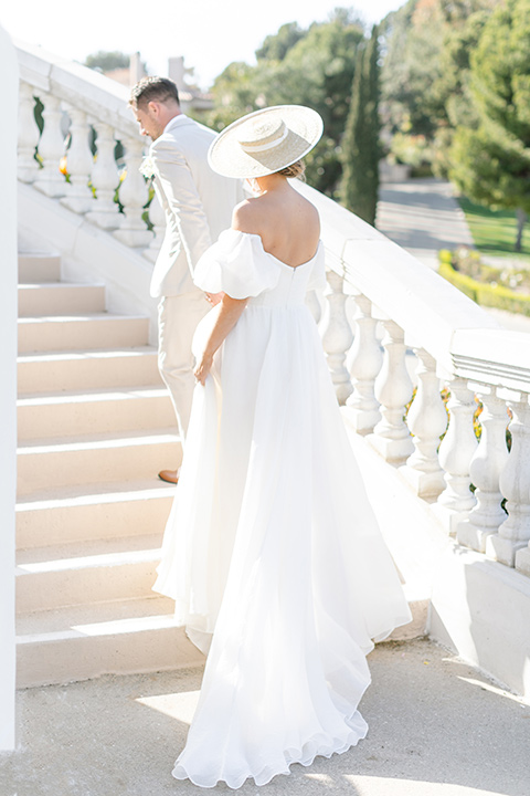  English garden romantic wedding with the bride in an off-the-shoulder gown and the groom in a tan suit – walking up the stairs 