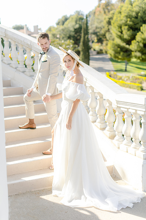  elevated cottagecore wedding design with the bride in a long sleeve ball gown and the groom in a tan suit - walking up the stairs 