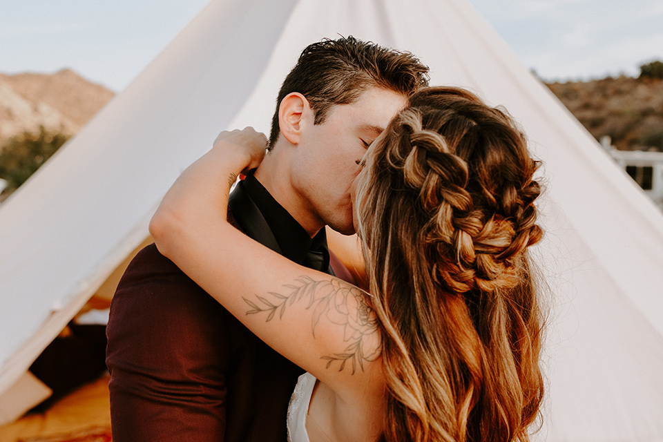  boho burgundy and beige wedding in the dessert – couple kissing in the tent 