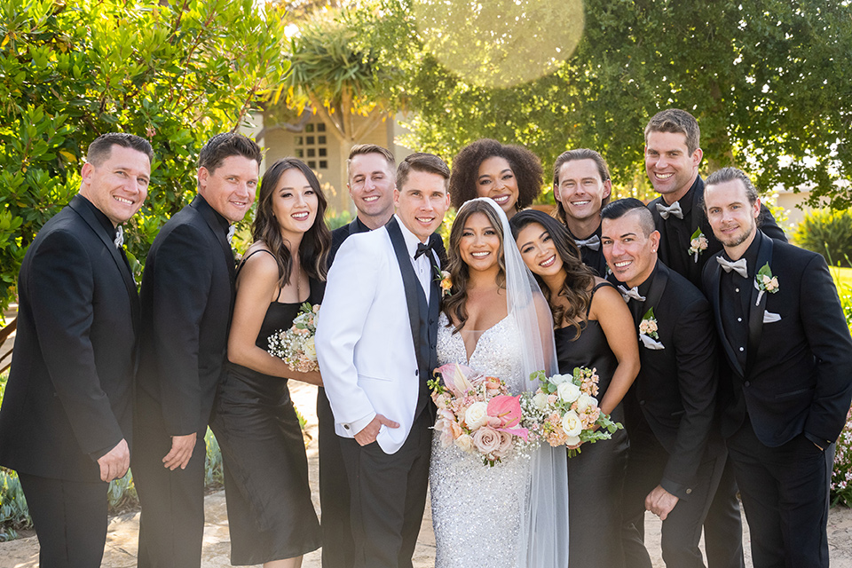  a modern black and white wedding with crystal details -the bride in a lace formfitting gown and the groom in a white + black tuxedo – bridal party