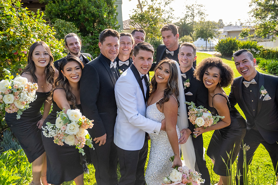  a modern black and white wedding with crystal details -the bride in a lace formfitting gown and the groom in a white + black tuxedo – bridal party